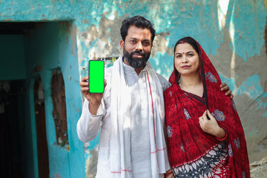 Rural indian couple showing smart phone with blank display standing together. Husband and wife holding mobile phone. Technology. Digital india