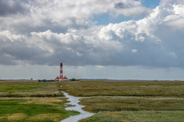 Striped Lighthouse on Grassy Landscape Under Dramatic Cloudy Sky