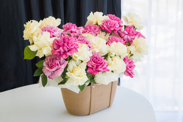Beautiful arrangement of pink and white roses in a woven basket on a table.