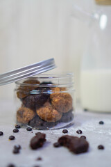 an open jar filled with cookies, surrounded by chocolate chips and milk bottles in the background
