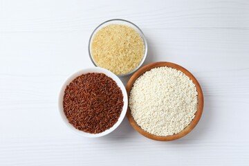 Different types of rice in bowls on table, top view