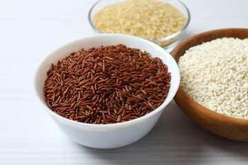 Different types of rice in bowls on table, closeup