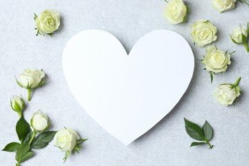 Beautiful white roses with paper heart on light background
