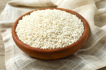 Raw white rice in a bowl on wooden background