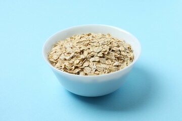 Composition with oatmeal flakes on blue background. Cooking breakfast