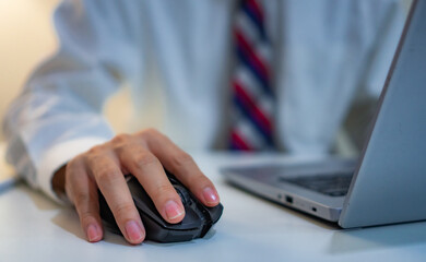 Close up hand of business man working on laptop computer by clicking on computer mouse on office...