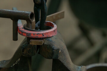 Creating a fishtail scroll in a blacksmith forge, bending the metal around a forma.
