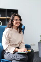 A woman is sitting in a chair with a book in her lap. She is smiling and she is enjoying her time