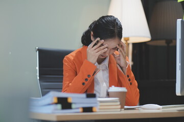 Young adorable Asian businesswoman working with work document during the night, working overtime at...