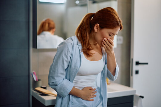 Mid adult woman feeling nauseous in morning in bathroom.