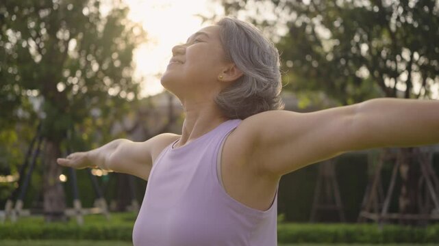 Asia adult aged people middle age mindful happy old woman open arm yoga deep calm stress relief outdoor nature public park sun light self love relax elder aging life asian female mental health care.