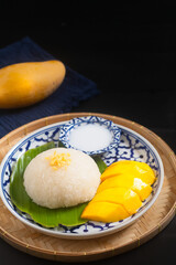 Food concept Thai authentic dessert Mango sticky rice classic Thai dessert on the ceramic plate on black background with copy space