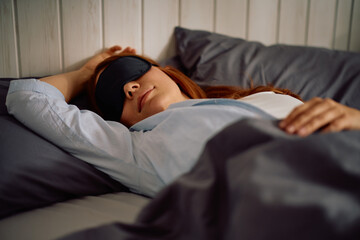 Mid adult woman wearing sleeping eye mask in bed.