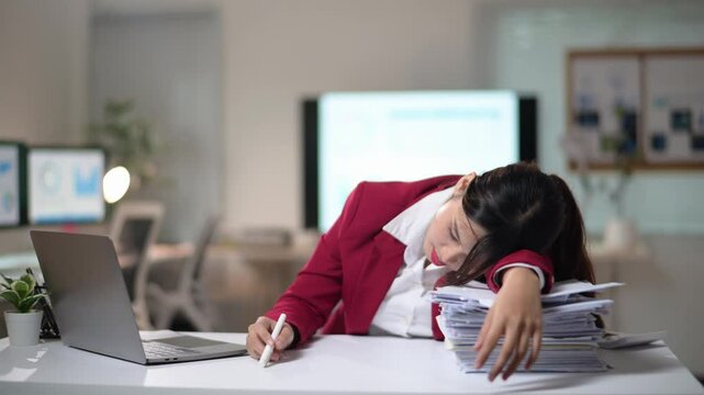 Asian businesswoman falling asleep on desk while working