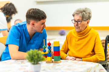 Male nurse assisting elderly woman with cognitive games in nursing home