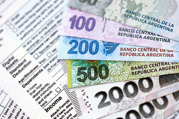 Argentine pesos money bills in big amount lies on table with pen and tax forms close up