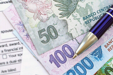 Argentine pesos money bills in big amount lies on table with pen and tax forms close up