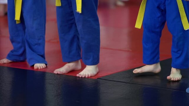 children in kimonos practice jumping. Children during training exercises. Close-up of children's legs in kimono jumping on tatami mats during martial arts classes
