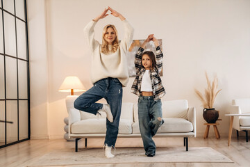 Fitness or yoga exercise. Mother and daughter are together in domestic room