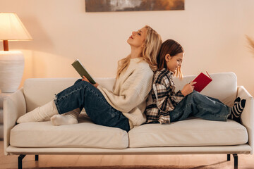 With books, reading time. Mother and daughter are together in domestic room