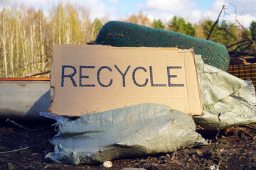 Recycling sign leaning on pile of garbage in forest