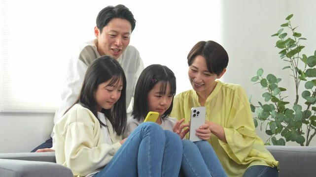 ソファに座り携帯を見る家族