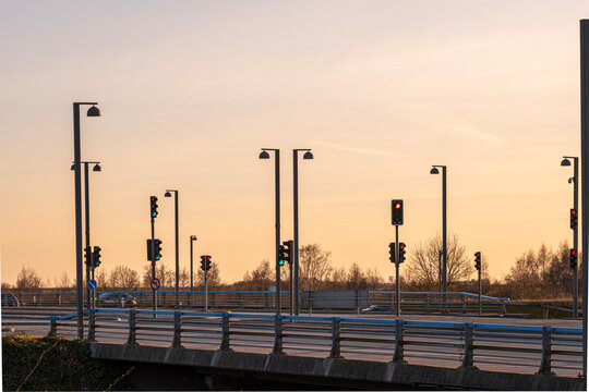 Row of urban streetlights along a highway at sunset in Copenhagen, Denmark. Golden hour lighting, minimal traffic and clear geometry, ideal for transportation, mobility and urban concepts.