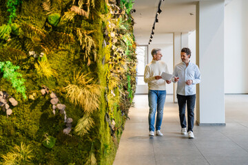 Two men having a business discussion in an office with a green wall