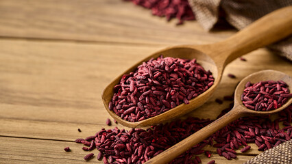 closeup pile of ferment red yeast rice or Angkak in wood scoop on wooden table rustic food background with copy space