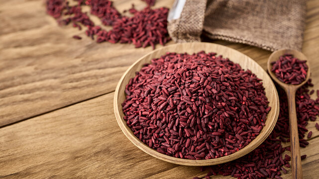 closeup pile of ferment red yeast rice or Angkak in wood bowl on wooden table rustic food background with copy space