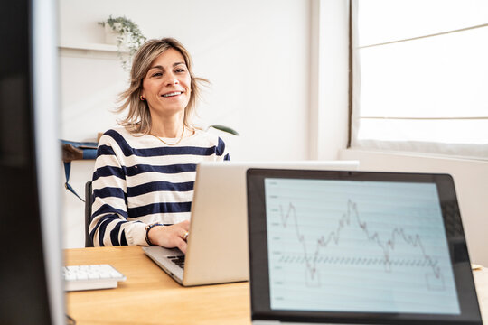 Businesswoman working on a laptop with a graph on the screen in an office