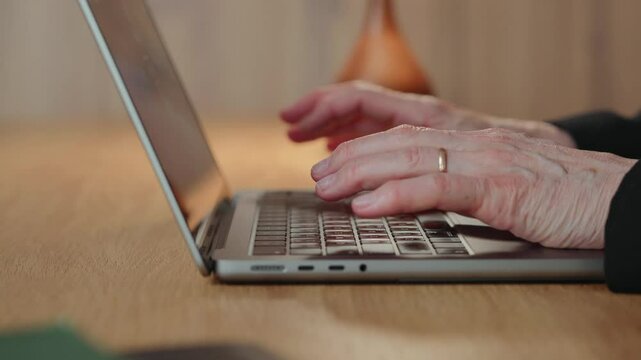 Close-up of a 60-year-old senior businesswoman hands as she types on a laptop. Her movements are precise and steady, showing professionalism and digital fluency in remote work. 4k footage