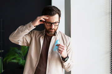 Sad manager with blue ribbon holding head suffering from headache