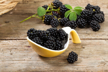 Blackberries on serving spoon and behind on wooden table