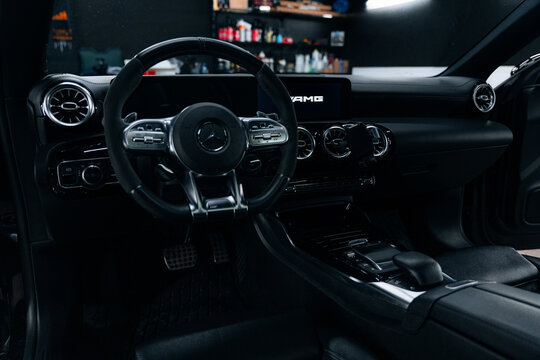 Interior view of Mercedes-Benz CLA 45 S AMG C118 with illuminated dashboard and ambient lighting premium black leather seats, digital cockpit, and modern design for luxury driving experience showcase