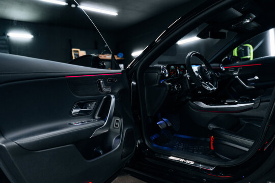 Interior view of Mercedes-Benz CLA 45 S AMG C118 with illuminated dashboard and ambient lighting premium black leather seats, digital cockpit, and modern design for luxury driving experience showcase