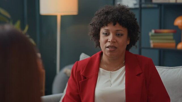 Tilt up shot of female African American psychologist talking to client during session indoors