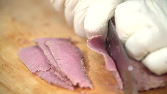 Cutting cooked beef with gloved hands