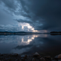 a dramatic thunderstorm approaching a calm lake, with dark clouds gathering in the sky and a few flashes of lightning in the distance