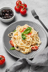 Delicious creamy spaghetti with cherry tomatoes, parmesan cheese and basil on a plate