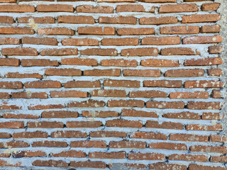 Background of a rough brick wall with uneven cement plaster, highlighting its rustic, unfinished texture