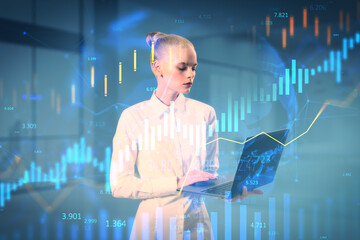 Businesswoman using laptop with financial data charts overlay on futuristic light background, creative modern finance technology concept design.