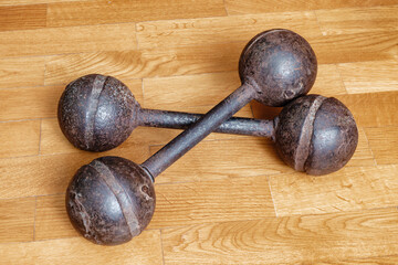 Vintage metal dumbbells on a wooden floor. The image symbolizes strength, sports, history, fitness,...