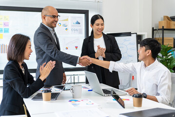 Happy diverse group Asian business working and shaking hands together after going through routine checks statistics financial. Group Team of business people meeting topic corporate concept in office.