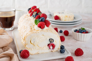 Meringue Pavlova roll cake with cream and fresh berries on top on a ceramic board on a concrete background. Copy space.