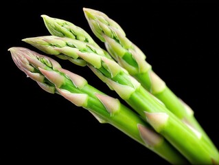 Close up of vibrant green asparagus bunch in diagonal alignment against black background showing texture detail and surface lighting