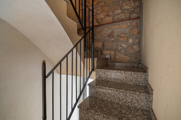 Rustic stairway with granite steps metal railing and stone textured wall in warm lighting