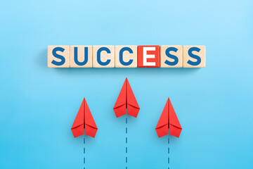 Business for success concept. success words icon on wooden cubes with group of red paper planes on...