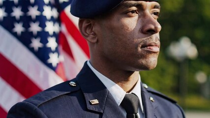Proud african american military veteran wearing uniform standing near waving american flag, representing national pride, service, and heroic commitment to country's freedom and values