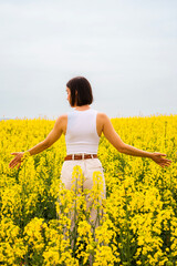Fototapeta premium Woman with open arms in a field of yellow flowers